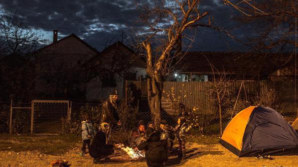 A group of Hazara refugees from Afghanistan warm themselves around a fire at the train station in Presevo, Serbia