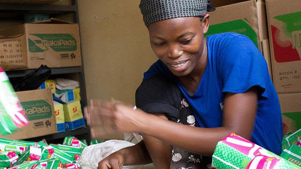 A young Ugandan woman stamps expiration dates on the bottom of hand-packaged MakaPad packets