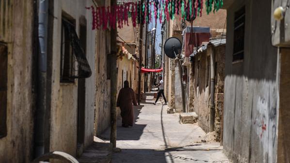 a woman walking down a narrow street in Amman