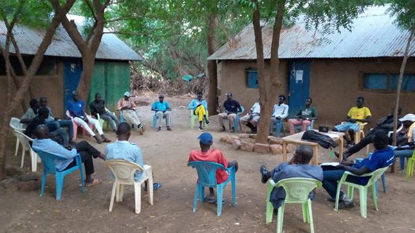Men sitting in a circle to discuss a dispute outside at Kakuma camp